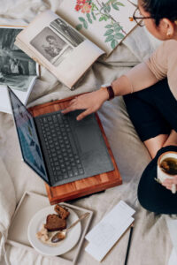 working with laptop, notes, and food on the bed