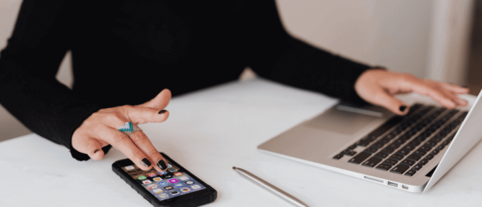 one man in black uses a phone and a laptop at the same time